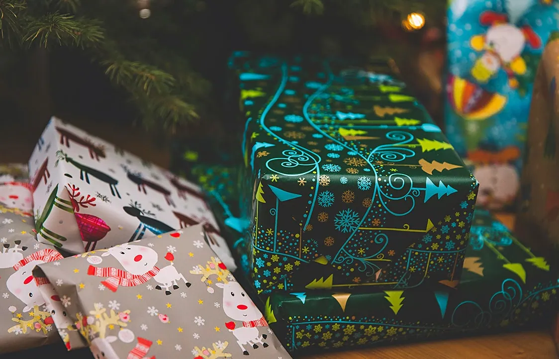 A close up of several 
presents underneath a Christmas tree.