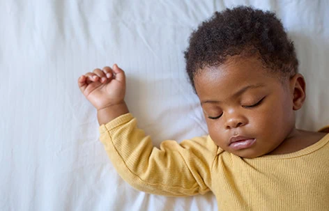 Adorable sleeping child in yellow pyjamas on a white bed. Perfect for children’s sleep and bedtime themes.