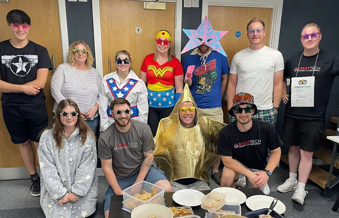 People wearing colourful superhero and star-themed costumes at team event.