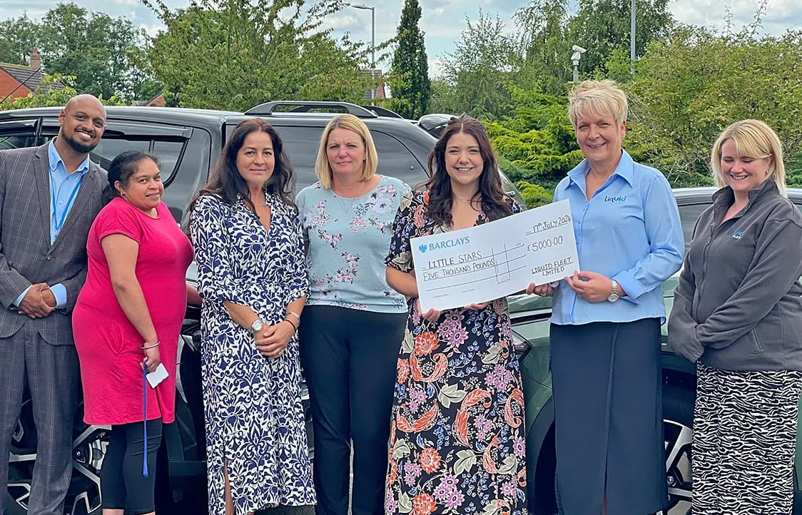 Diverse group of people holding a cheque for charity donation.