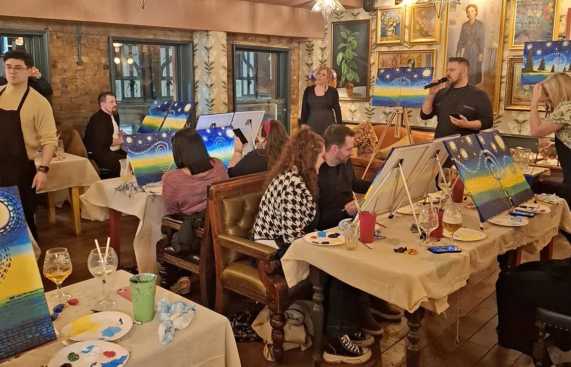 Bright starry night artwork at group painting party in cozy restaurant.