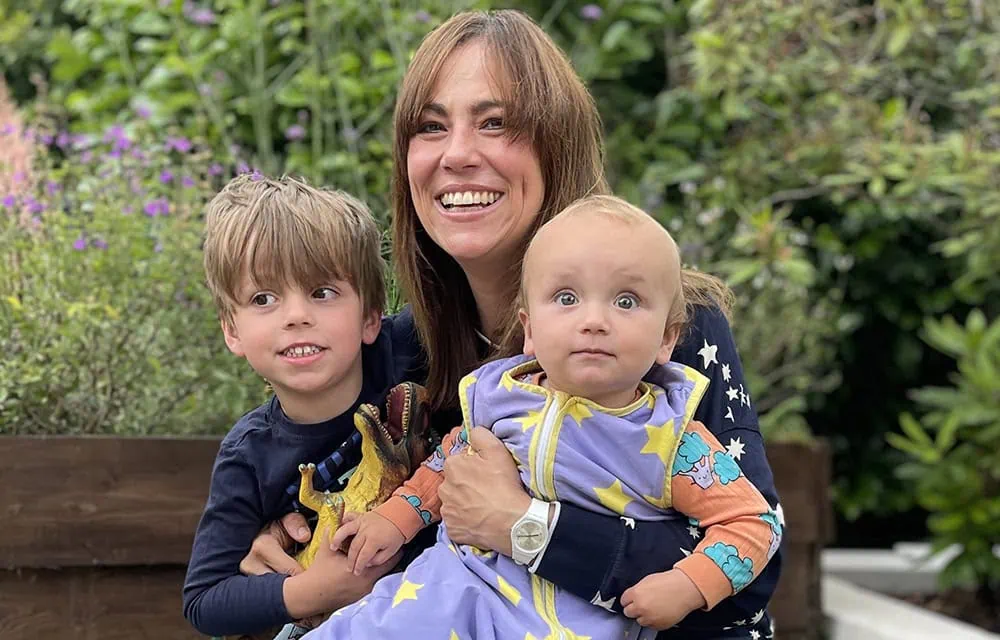 Happy family outdoors with young children and mother in garden setting.