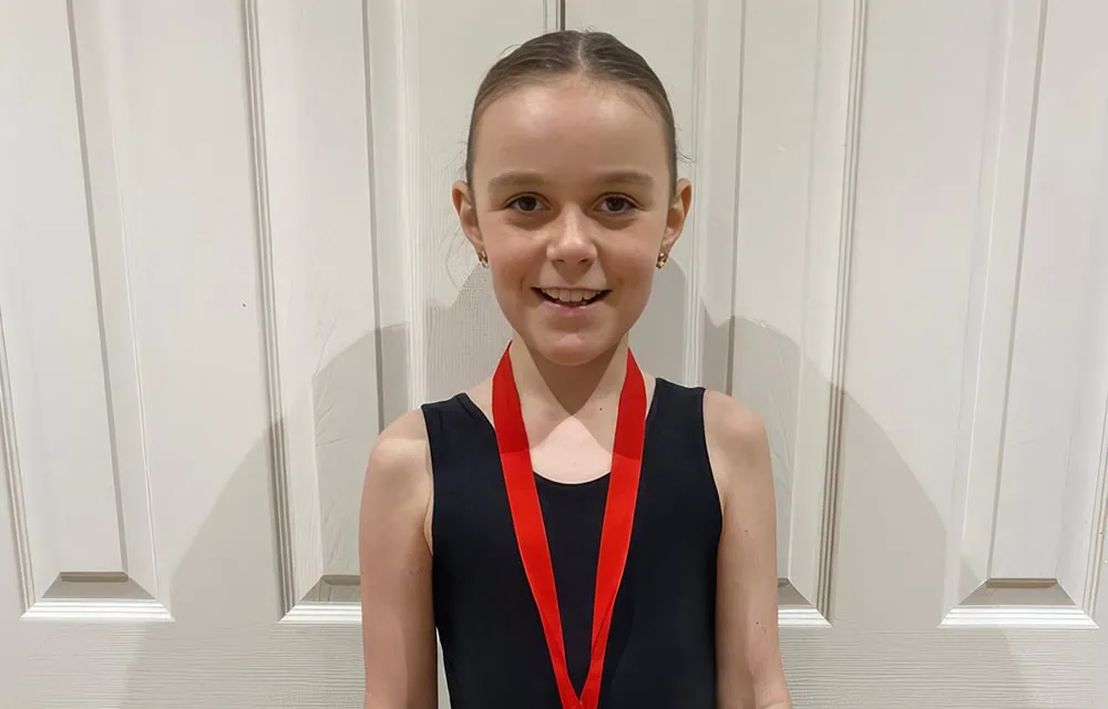 Young girl with athletic attire and medal, celebrating achievement.