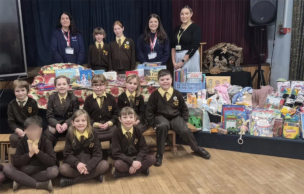 Bright children's charity event at school with kids and teachers displaying donations.