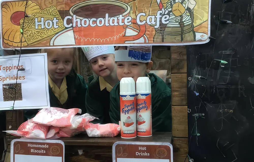 Child-friendly hot chocolate stand with kids in chef hats.