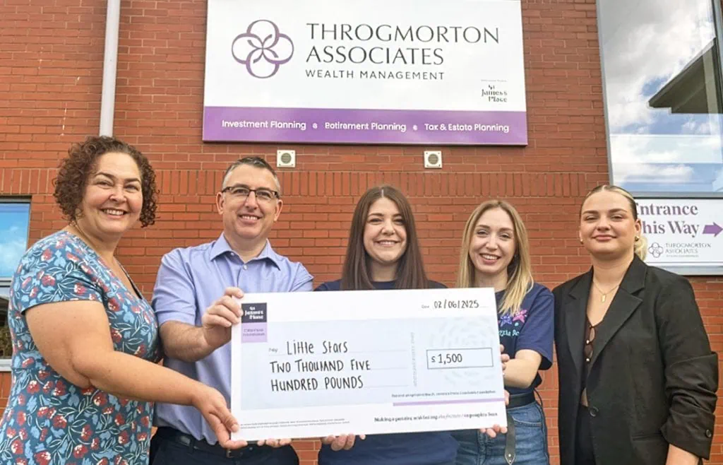Smiling group holding a donation cheque outside Throgmorton Associates office building.