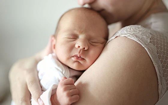 Close-up of newborn baby sleeping peacefully in mother's arms.