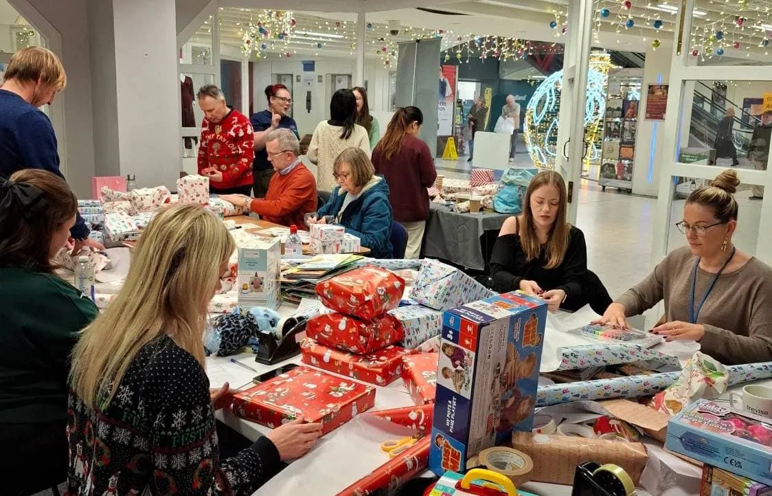 People wrapping presents at Little Stars during festive holiday event.