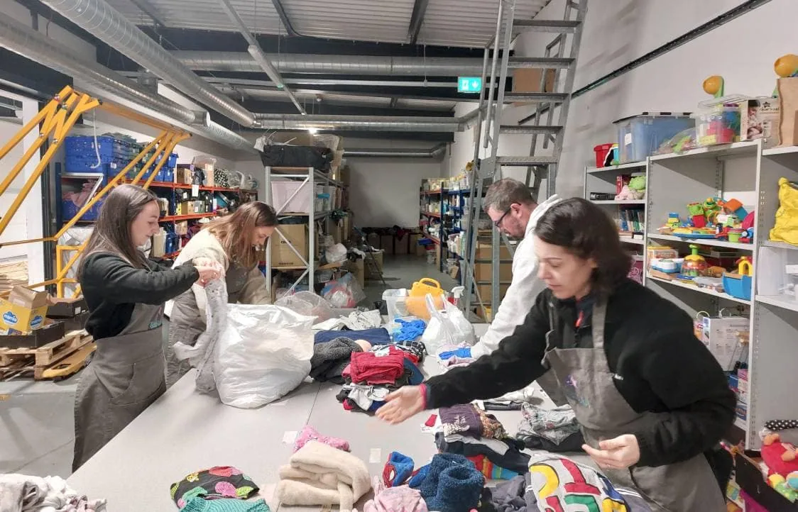 Charity volunteers sorting children's clothes at Little Stars warehouse.